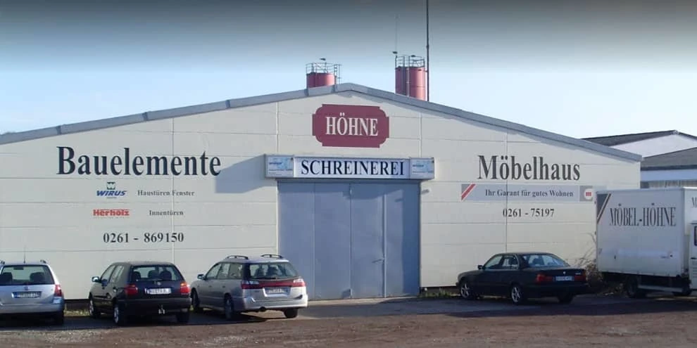 Fassade einer Schreinerei und Möbelhaus Höhne mit parkenden Autos davor.